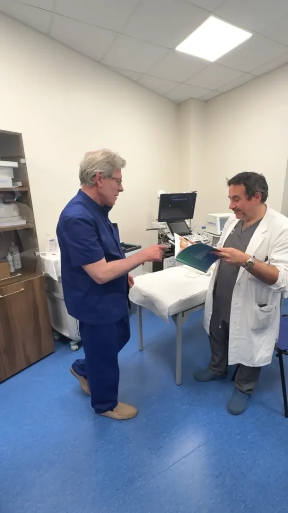 Professor Mykhailo Bolgov showing a copy of the atlas to an Italian doctor in a medical office.